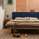 Modern bedframe with navy blue upholstered headboard and wooden base in stylish bedroom