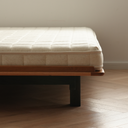 Minimalist wooden bedframe from Born in Colour with black legs and cream quilted mattress on parquet floor