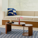 Modern wooden coffee table with unique oval and round design on blue patterned rug in living room